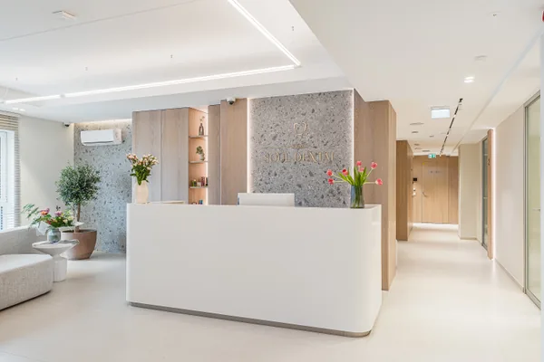Receptionsdisken på Soul Dental Studio: vit disk, klinikens logotyp på stenvägg, färska blommor
