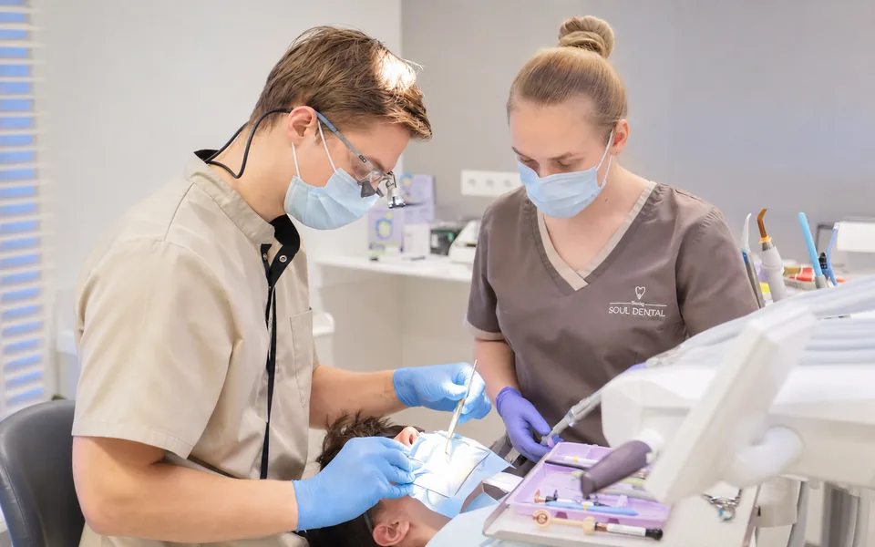 A dentist and an assistant treating a patient in the surgery